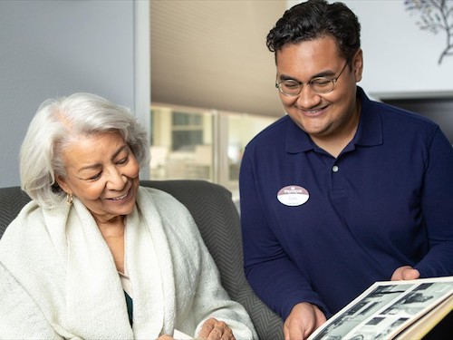 Primrose Memory Care resident showing interested staff member a photo album