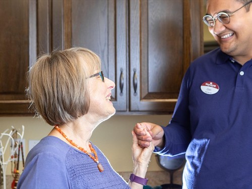 Primrose Memory Care resident being assisted and holding hands of caring staff member