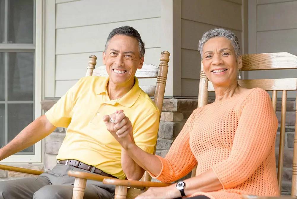 Senior couple sitting in rocking chairs outside their townhome villa