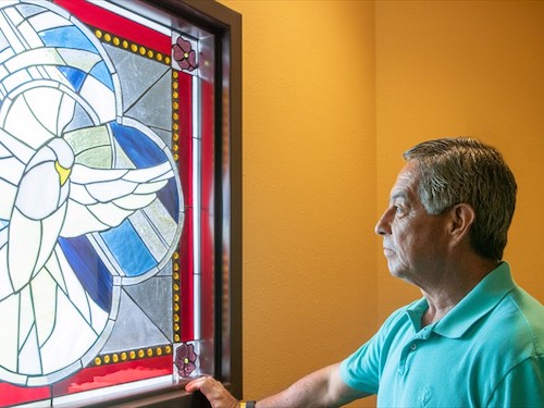 Family member of a Primrose Memory Care resident reflecting while looking at a stained glass window