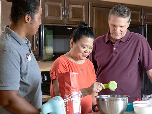 Two seniors making cookies with a staff member