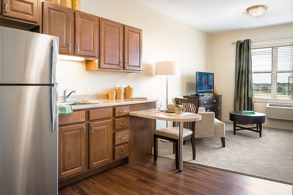 Kitchenette and living room area of a resident apartment in the Pleasant Prairie, WI Primrose Retirement Community.