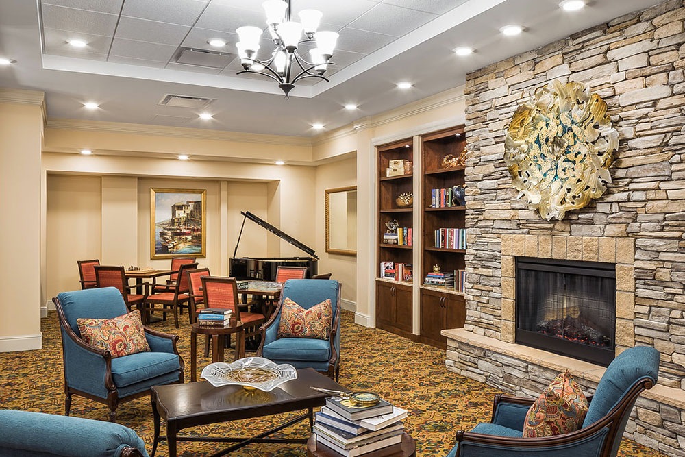 Piano and bookshelf in a fireside seating area at the Pleasant Prairie, WI Primrose Retirement Community.