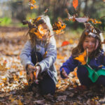 Grandkids having fun outside while throwing fall leaves up in the air.