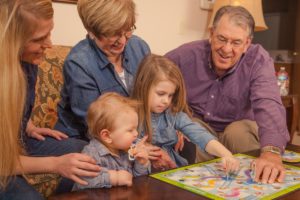 Family playing board game with senior living resident