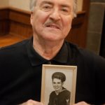 Senior man holding picture of himself when he was young