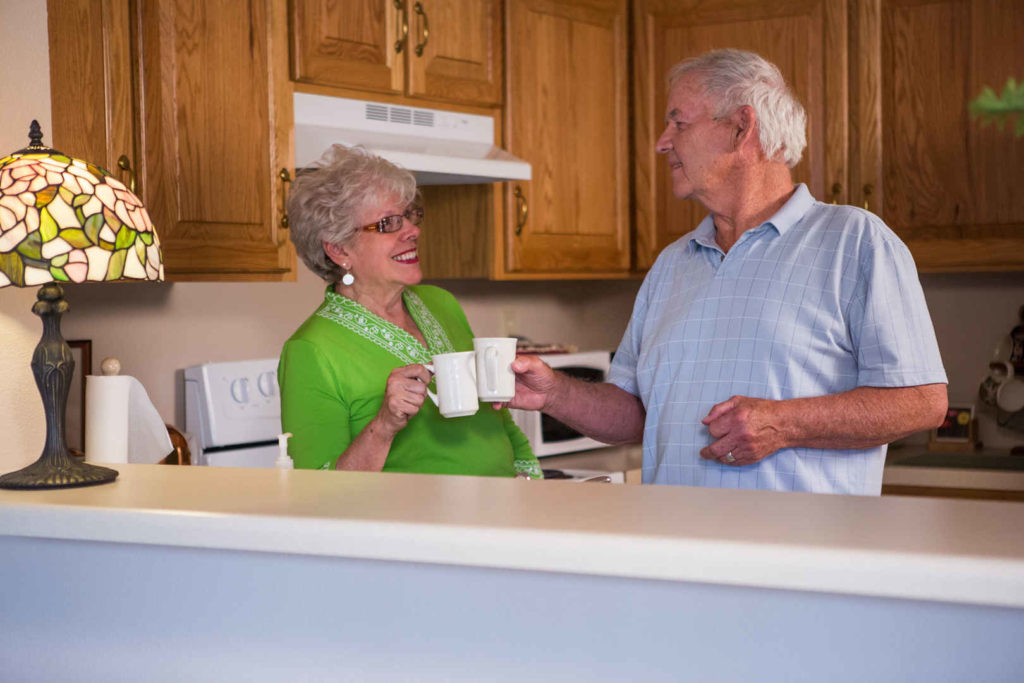 Older couple in kitchen having a cup of coffee.