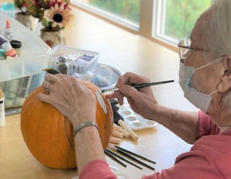 Senior woman painting pumpkin