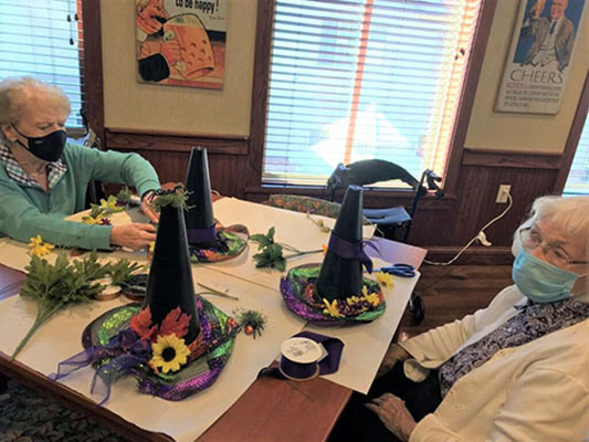 Senior women decorating witch's hats together