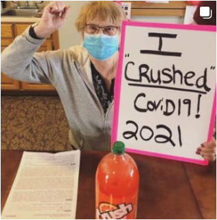 Woman holding a 'I crushed Covid19 2021' sign