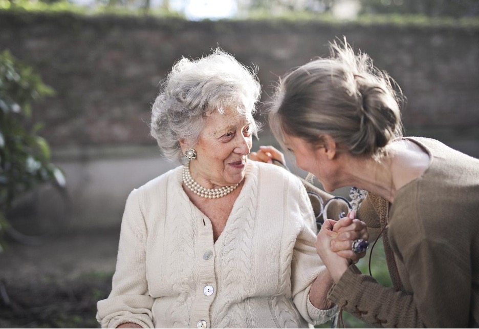 Older adult smiling with adult daughter; memory care.