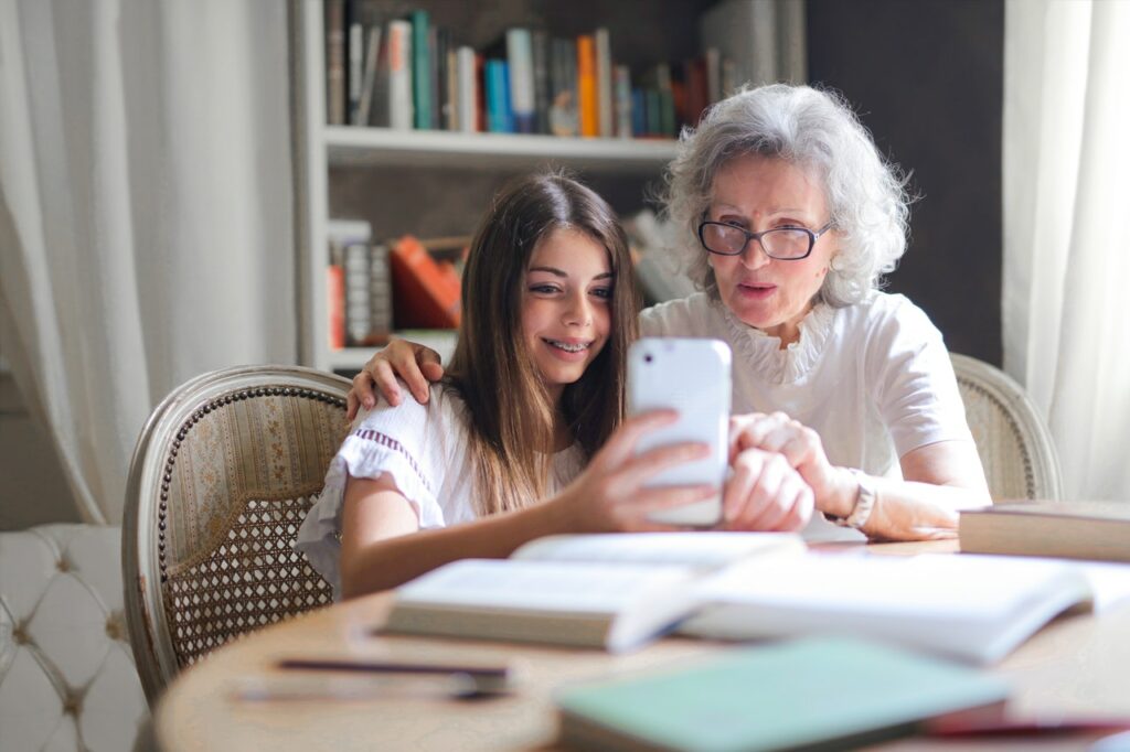 Older woman looking at smartphone with granddaughter.