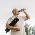 Man with diabetes drinking out of water bottle outside.