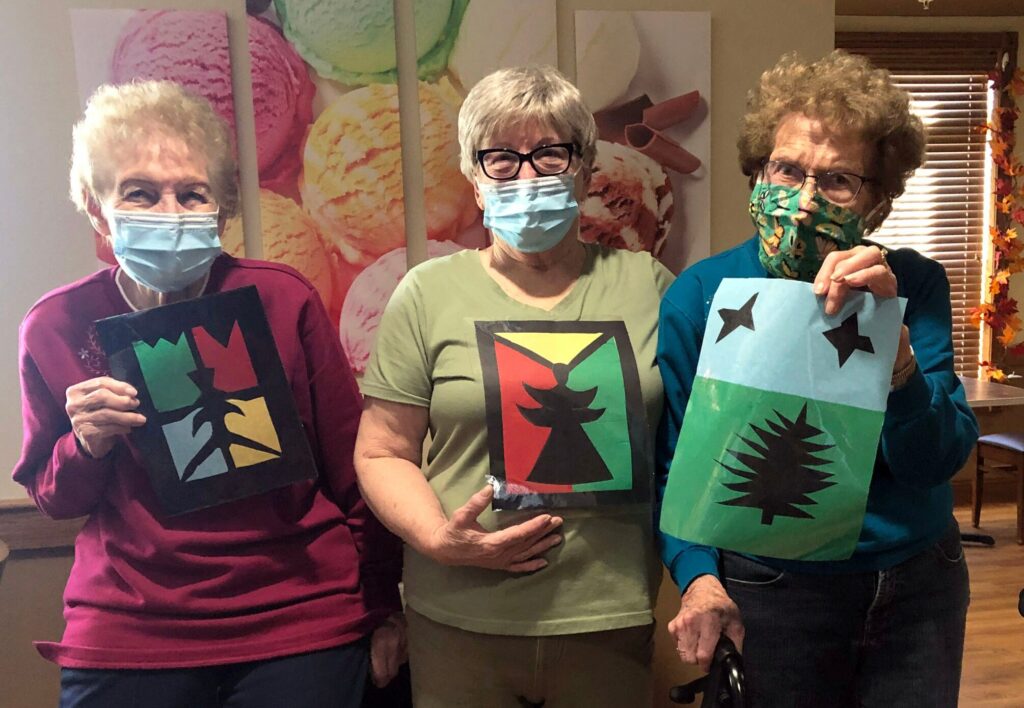 Three female Primrose residents holding up artwork