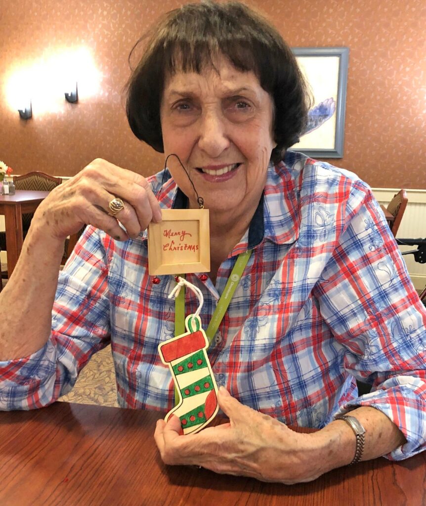 Primrose resident holding up Christmas stocking decoration that says Merry Christmas