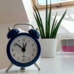 Alarm clock set to Daylight Savings Time on table in front of window.