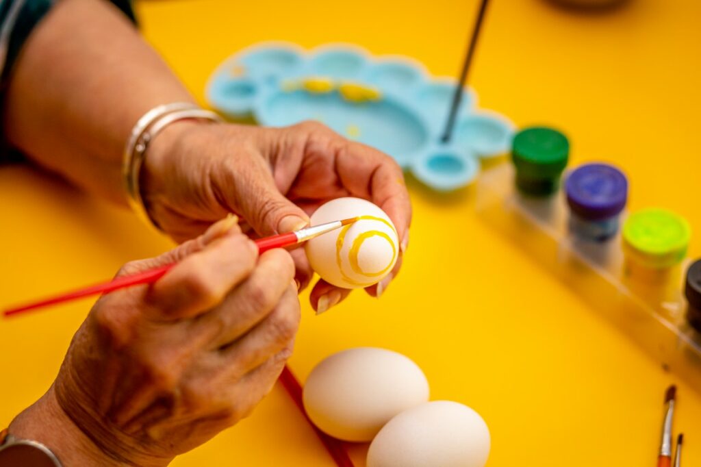 Older woman painting an Easter egg to celebrate the holiday.
