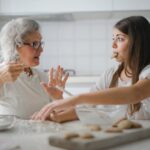 An elderly woman baking cookies with young teenager.