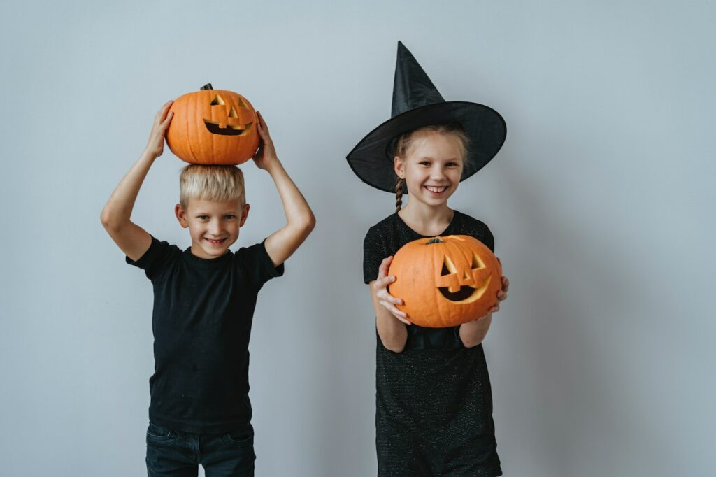 A young granddaughter and grandson holding freshly carved pumpkins.