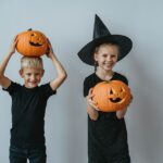 A young granddaughter and grandson holding freshly carved pumpkins.