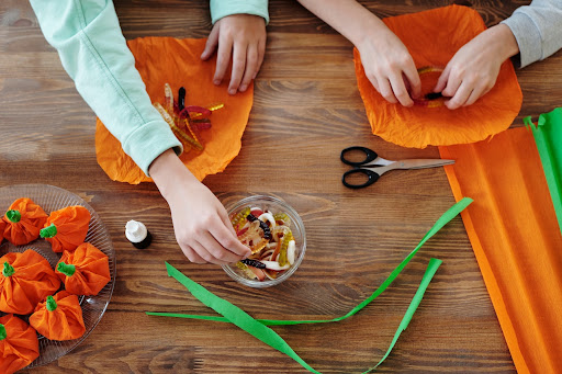 Two grandchildren making pumpkin crafts with tissue paper.