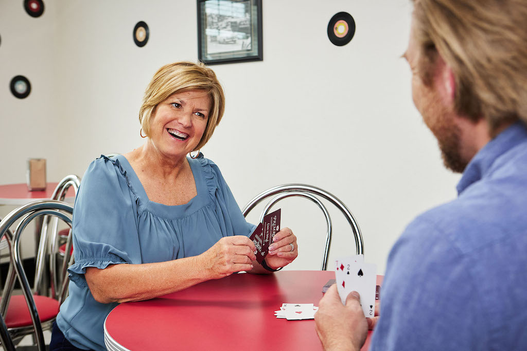 Primrose staff member playing a game of cards with resident to help fight loneliness.