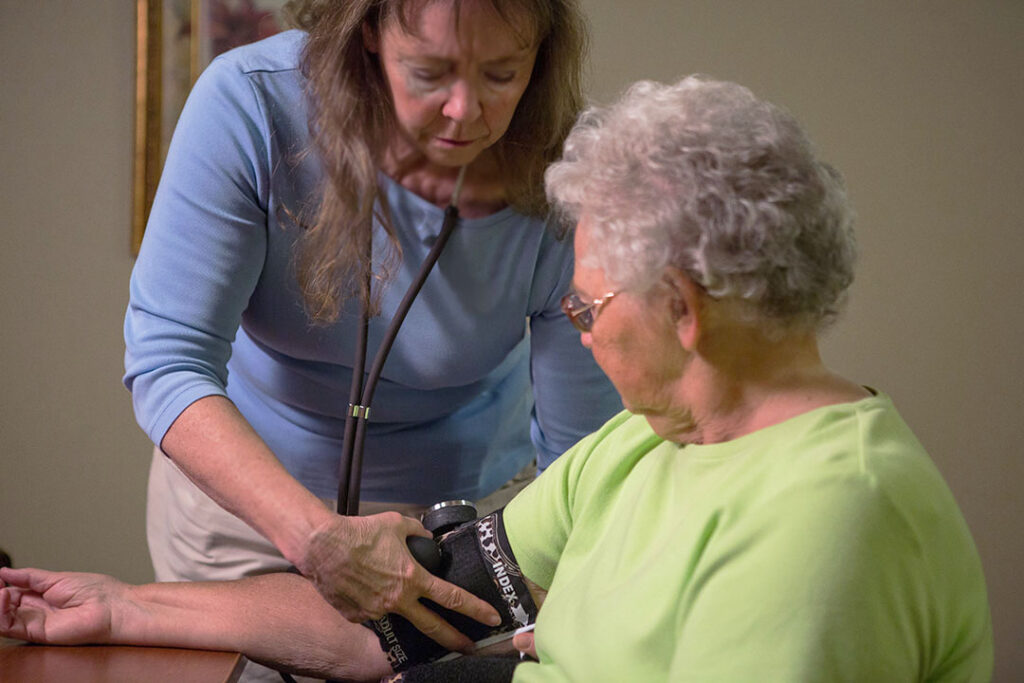 Staff member taking the blood pressure of an assisted living resident