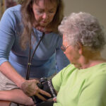 Staff member taking the blood pressure of an assisted living resident