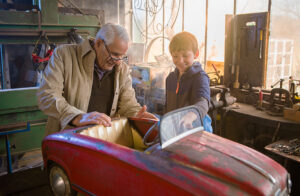 Grandfather with grandson working on a toy car in the workshop