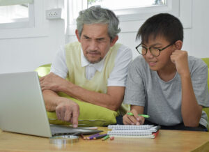 Grandfather working on a computer with his grandson
