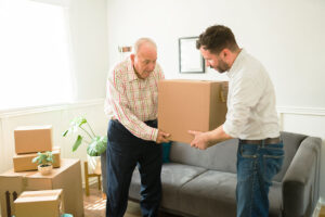 young man helping his elderly father pack boxes to move