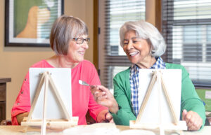 Two senior women enjoying a painting activity