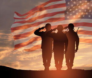 USA army soldiers saluting on a background of sunset or sunrise and USA flag. 