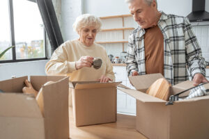 Senior couple placing items into a box as they pack to move to a senior living community