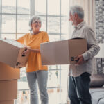 Senior couple carrying boxes that are packed to be moved into a senior living facility