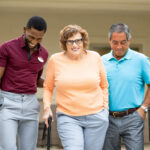 Senior couple walking outdoors with staff member