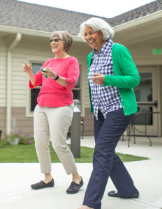 Two senior women playing a yard game in the outdoor courtyard