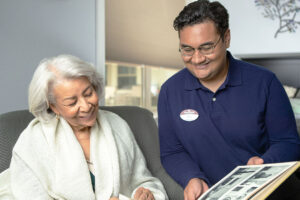 Resident and staff member reminiscing as they look through a photo album.