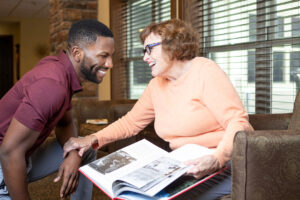 Staff member with female senior resident reminiscing over a book.