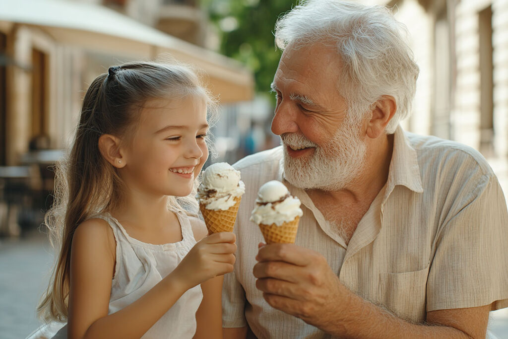 A grandpa and granddaughter eating ice cream together.