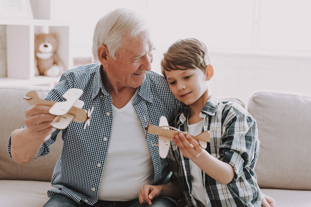 A grandpa and grandson playing with toy planes that they made together.