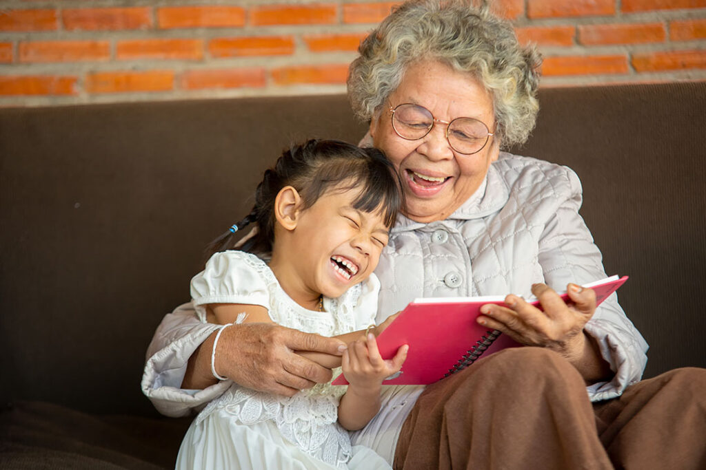 A grandma and granddaughter laughing as they read a story together
