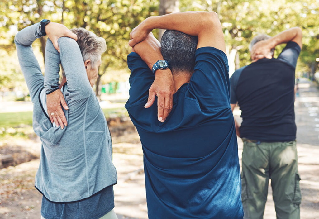 A senior group of friends stretching outside before doing a workout.